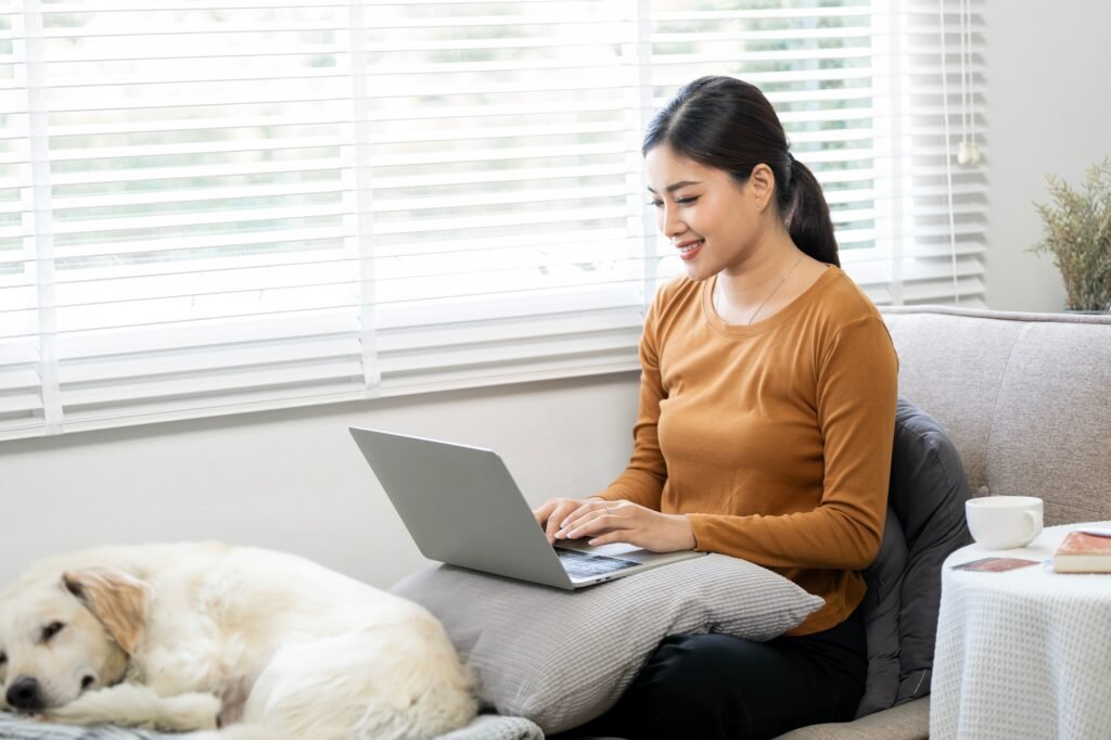 Businesswoman working on laptop computer sitting at home with a dog pet