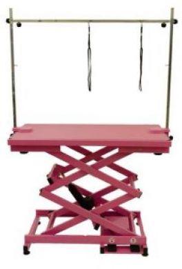 K9 Trailer Rentals The Electric Grooming Table N-109X is a pink adjustable table with a scissor-lift base and metal overhead arm, featuring two hanging loops to secure animals during grooming.