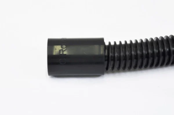 K9 Trailer Rentals A close-up of a black corrugated plastic hose with a smooth cylindrical connector on one end, set against a plain white background.