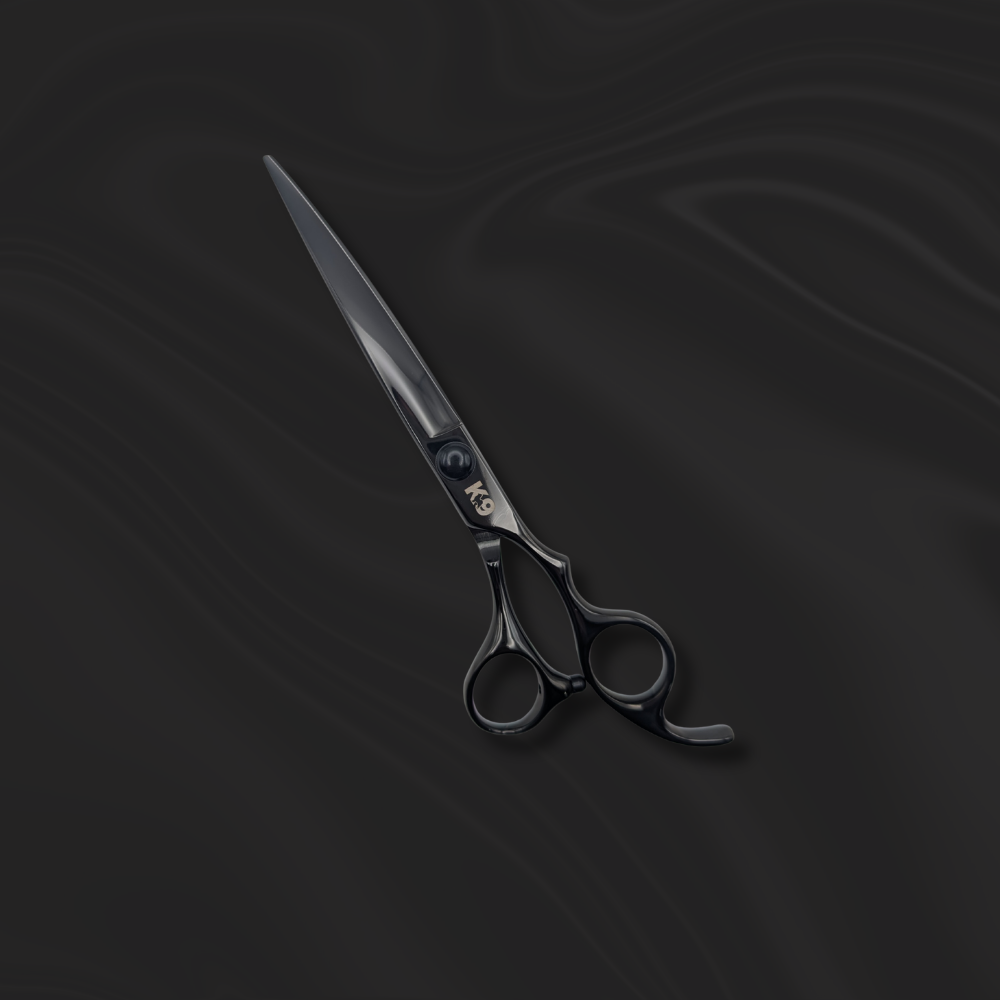 K9 Trailer Rentals The 7″ Black 440C Steel K9 Curve Scissor, featuring a shiny finish, rests on a smooth, dark, wavy surface.